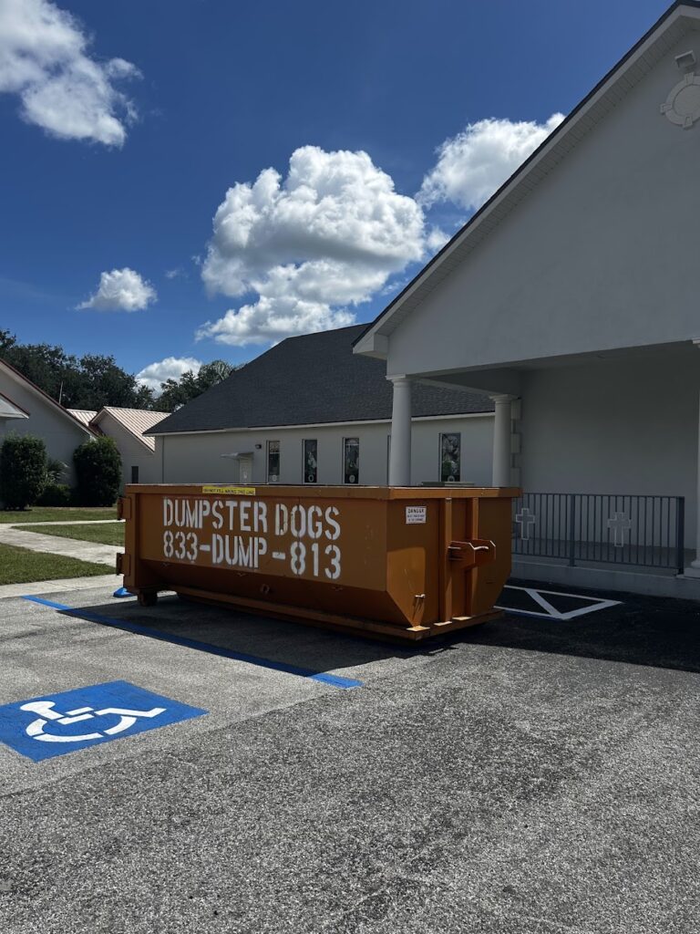 A Dumpster Dogs roll-off container staged in a paved commercial lot